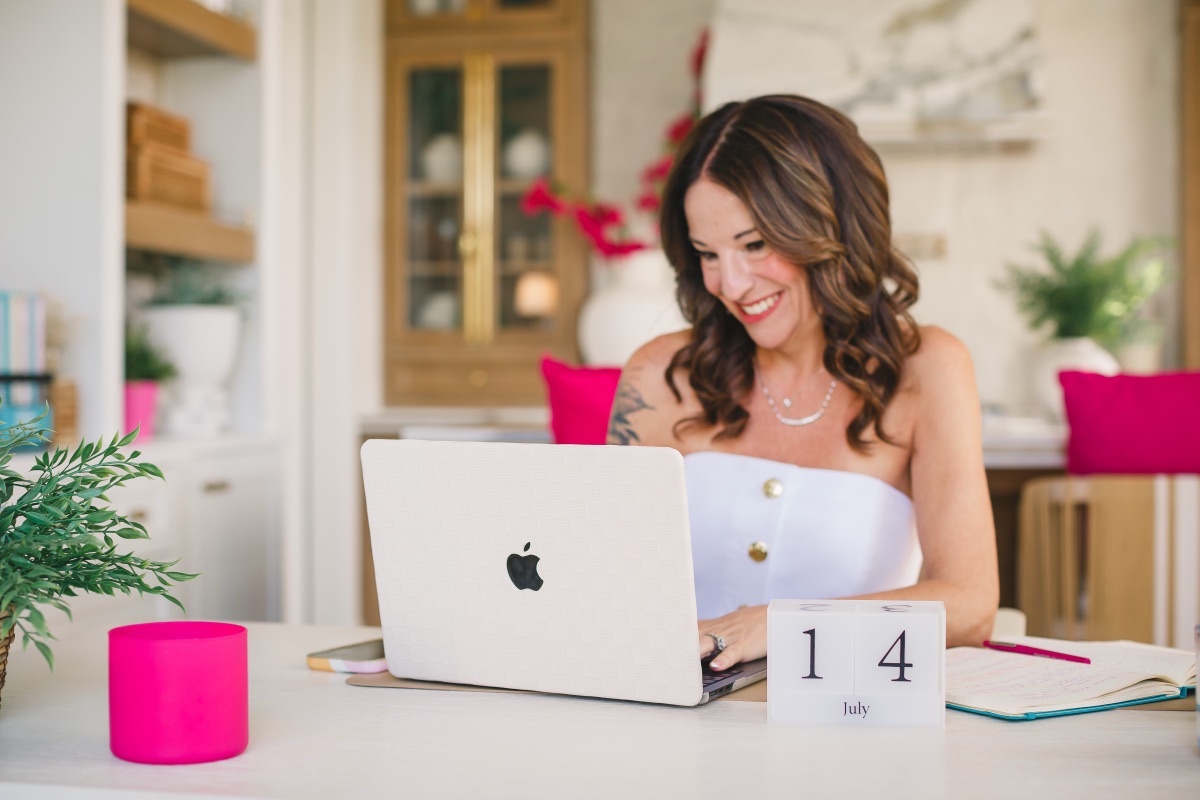 Jamie smiling at her laptop with a wooden calendar block showing July 14